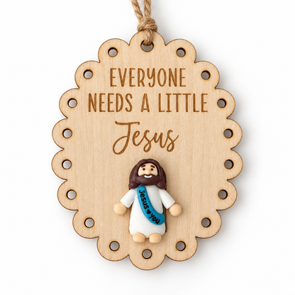 Scalloped Everyone Needs a Little Jesus wooden ornament with mini Jesus figure and rustic twine