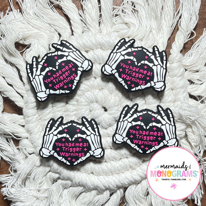 Four skeleton hand beads with text on a textured white surface, featuring the brand 'Mermaids & Monograms'.